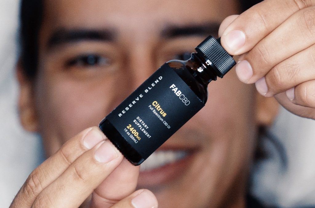 Photo: A smiling man holds a bottle of CBD oil.